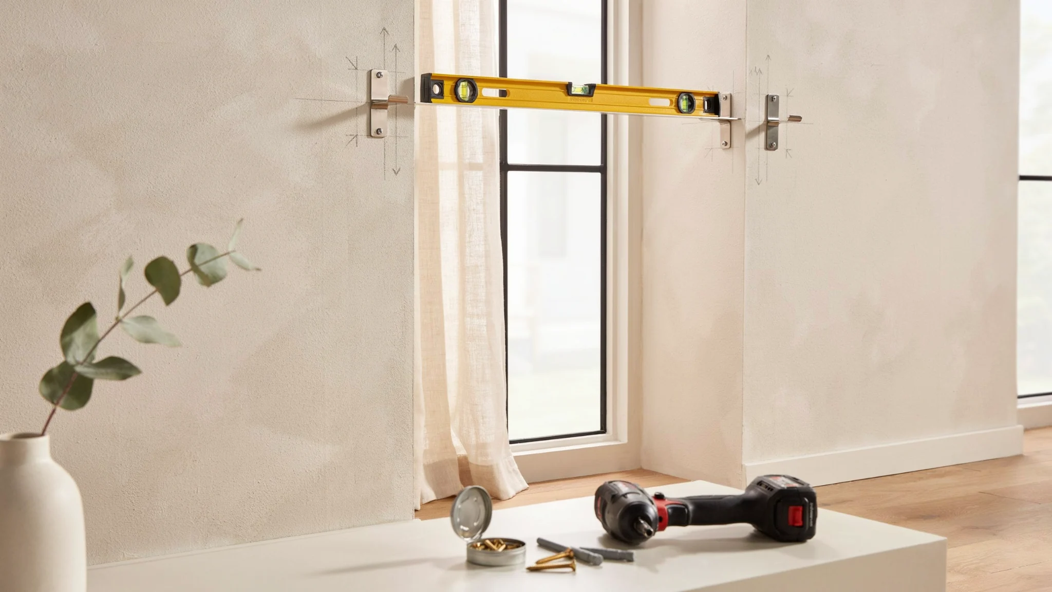 "Installed curtain rod brackets aligned with level and tools during grommet curtain setup in modern interior"