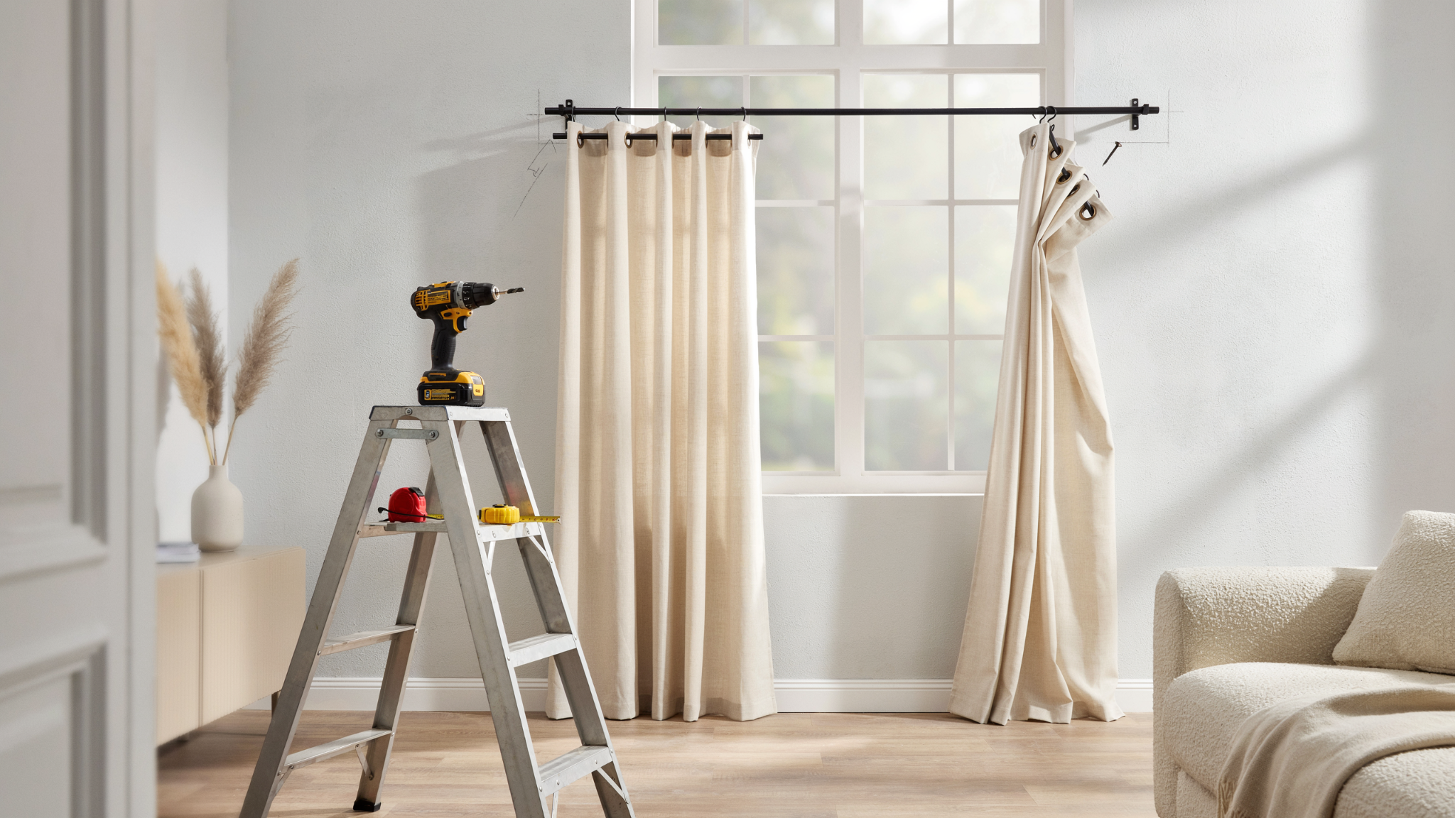 "Partially installed grommet curtains on window with curtain rod brackets and drill on ladder in modern living room interior"