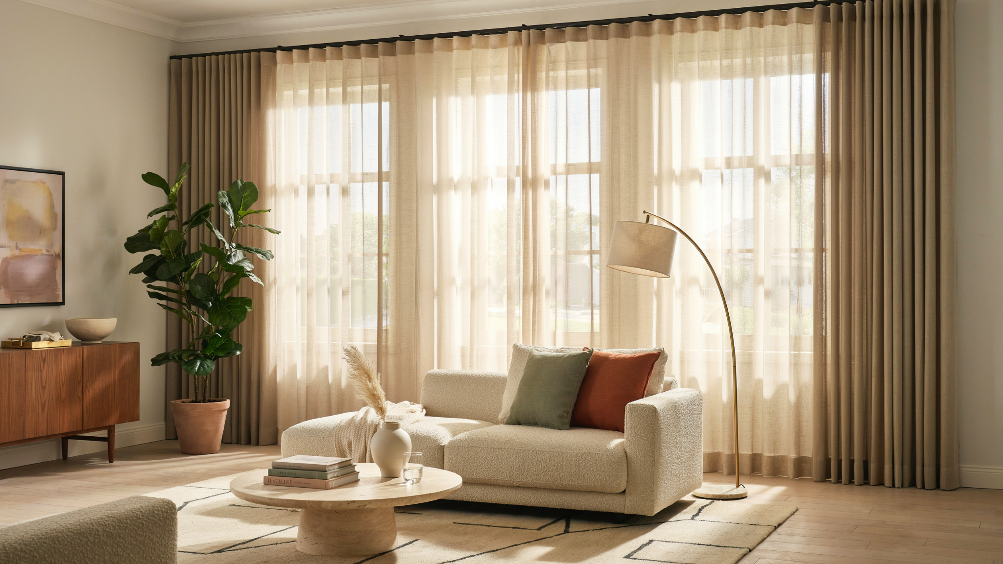 Three windows with a double curtain rod setup featuring layered sheer and solid curtain panels.