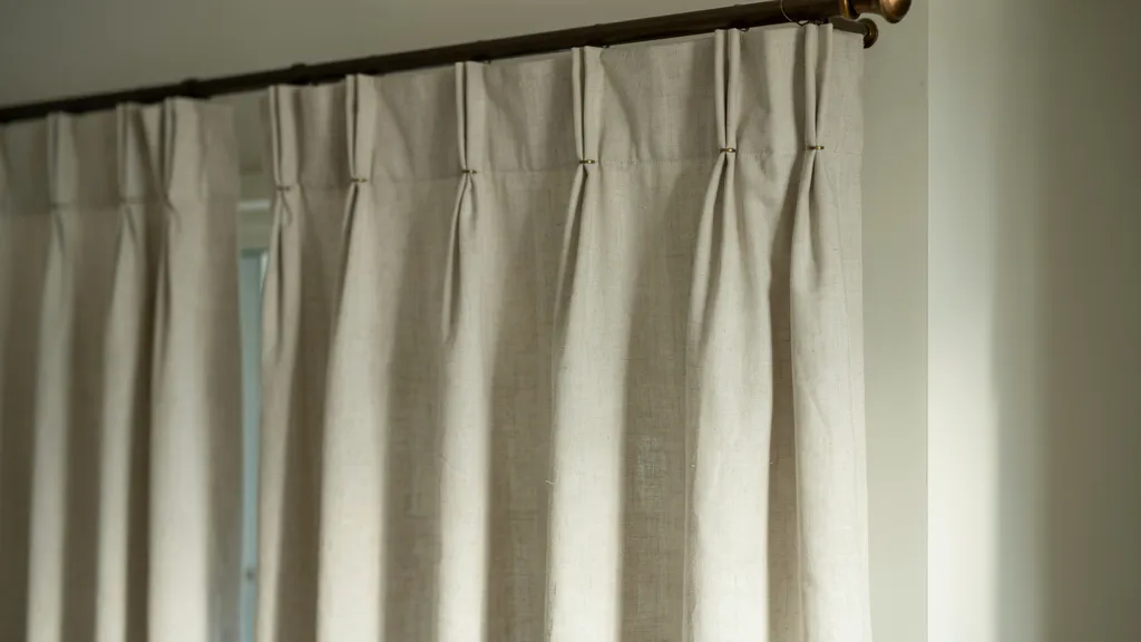 Close up view of curtain pleats stitched into fabric panels showing how folds control draping light flow and create structured or relaxed interior styling effects.