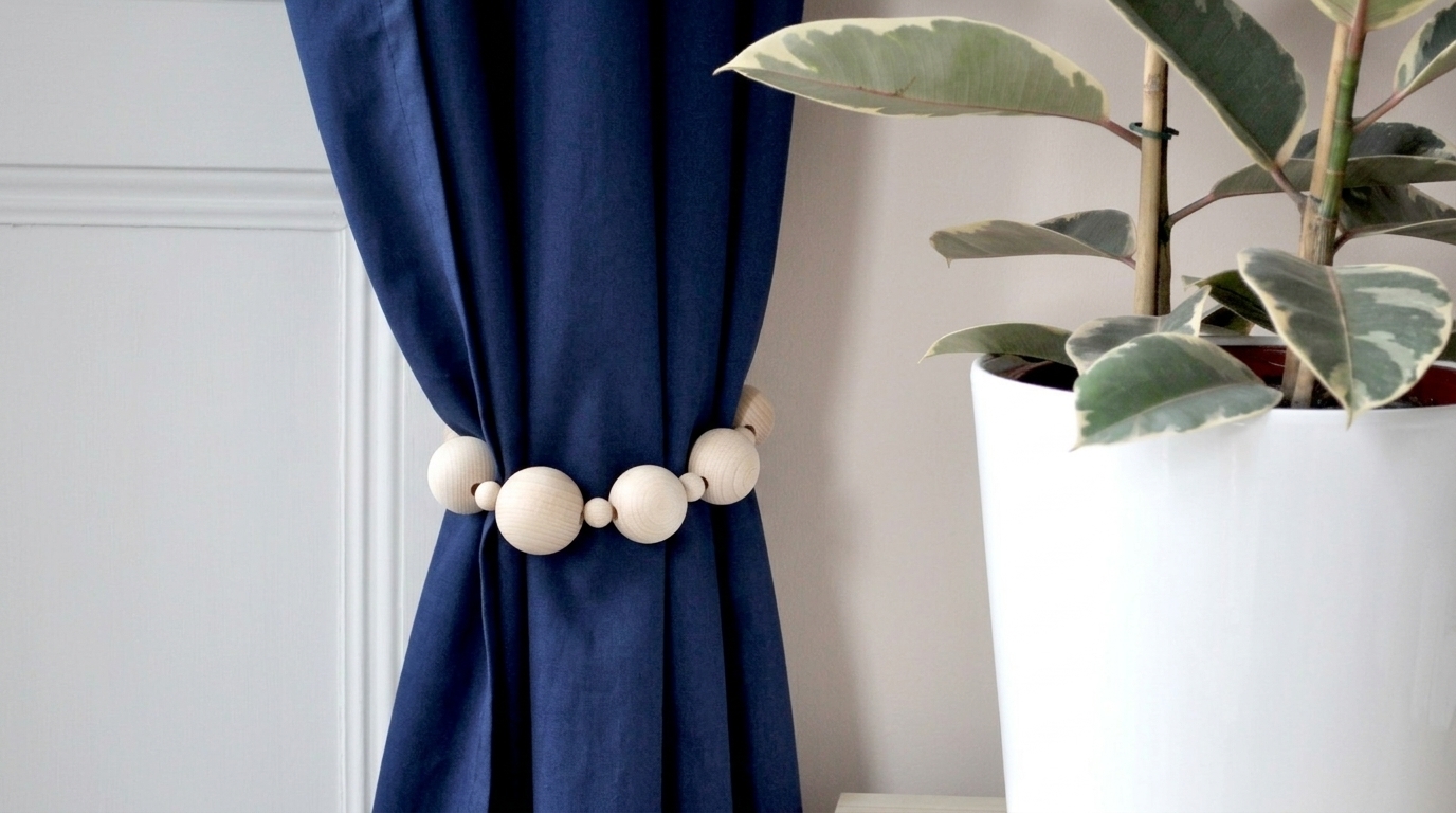 A deep navy curtain held back by a handmade tie back made of large natural wooden beads.