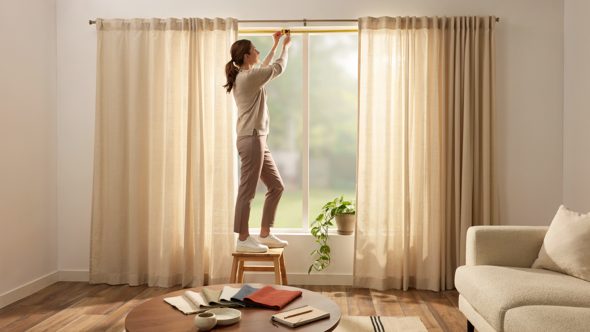 Person measuring a window to determine the correct number of curtain panels in a bright and modern home.