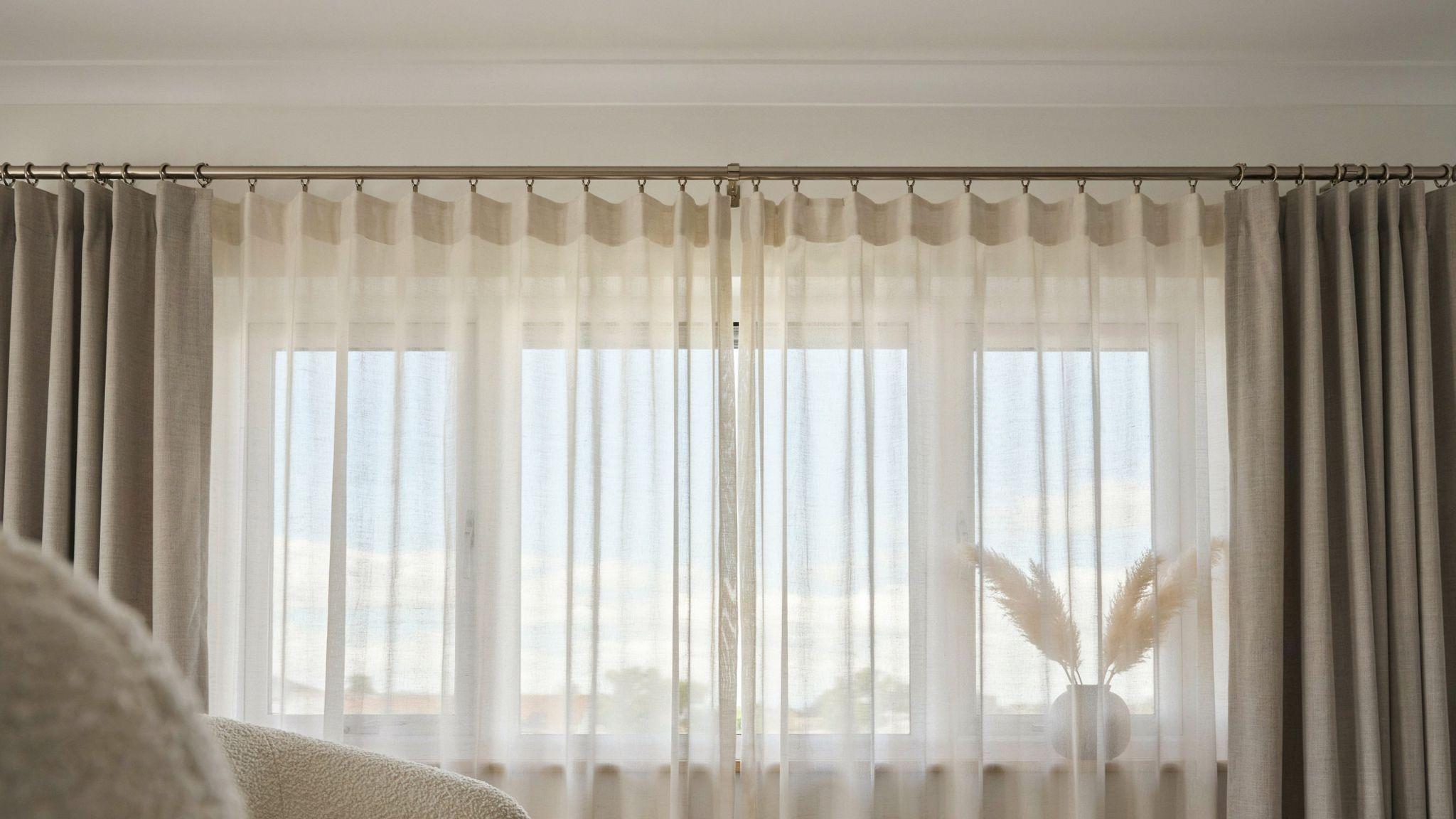 Sheer curtains attached with rings behind drapes on a single curtain rod