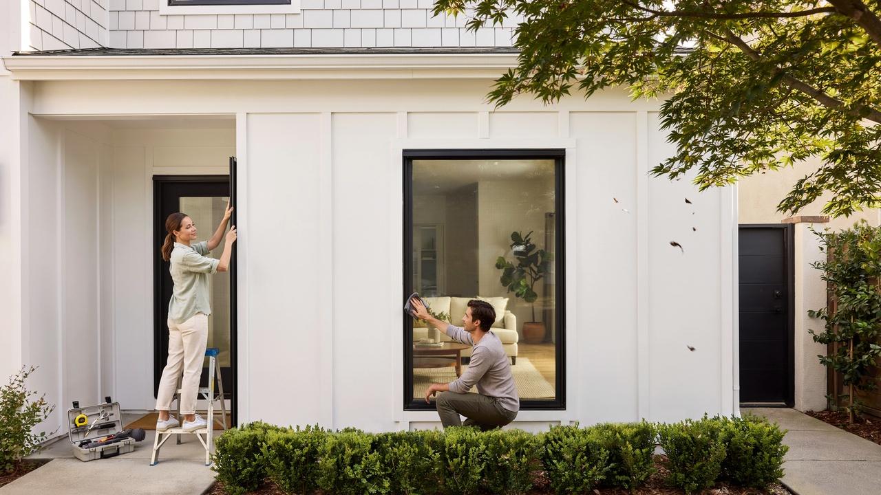 Homeowners installing and cleaning solar screens on windows, highlighting easy setup and maintenance.