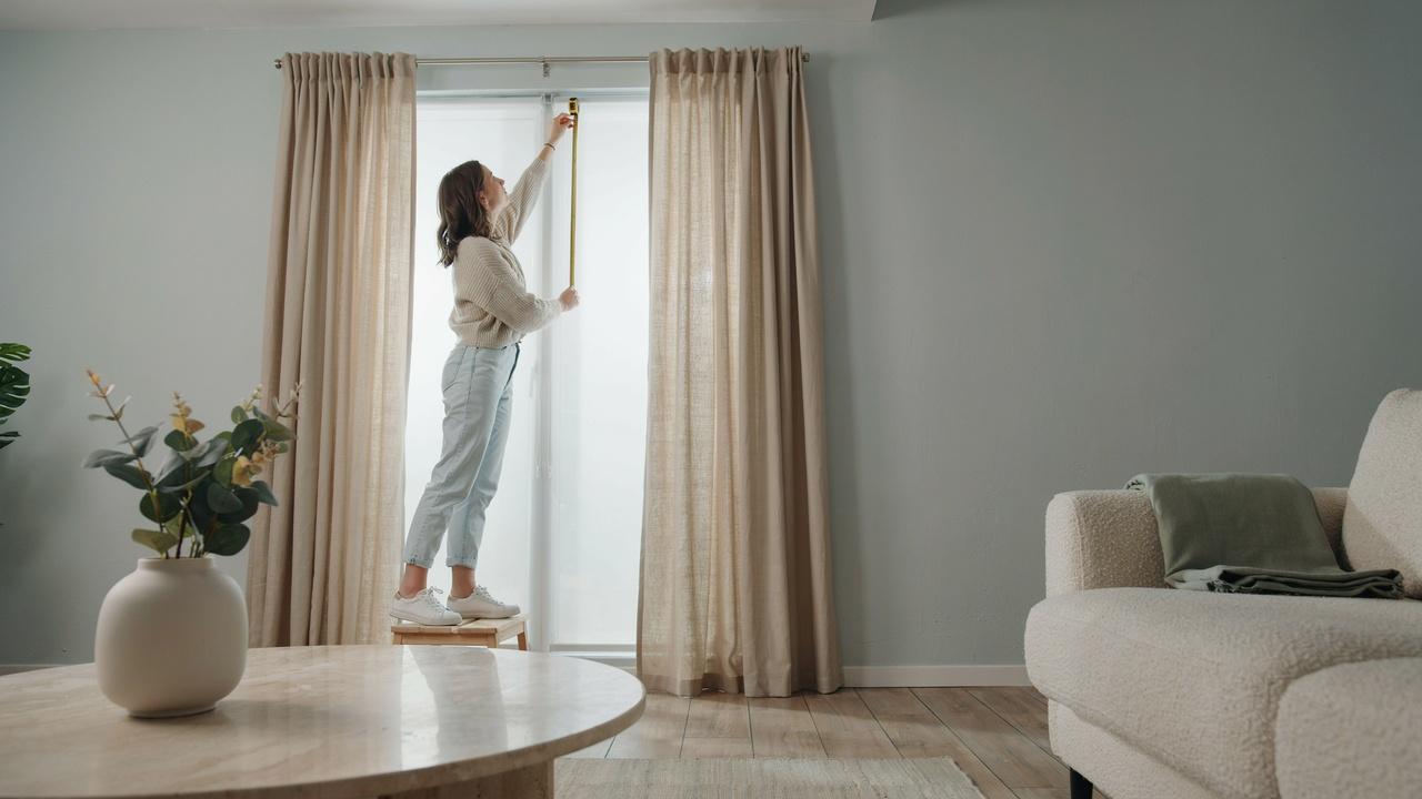 Modern window with a curtain rod installed high above the frame and floor-length curtains demonstrating proper hanging height.