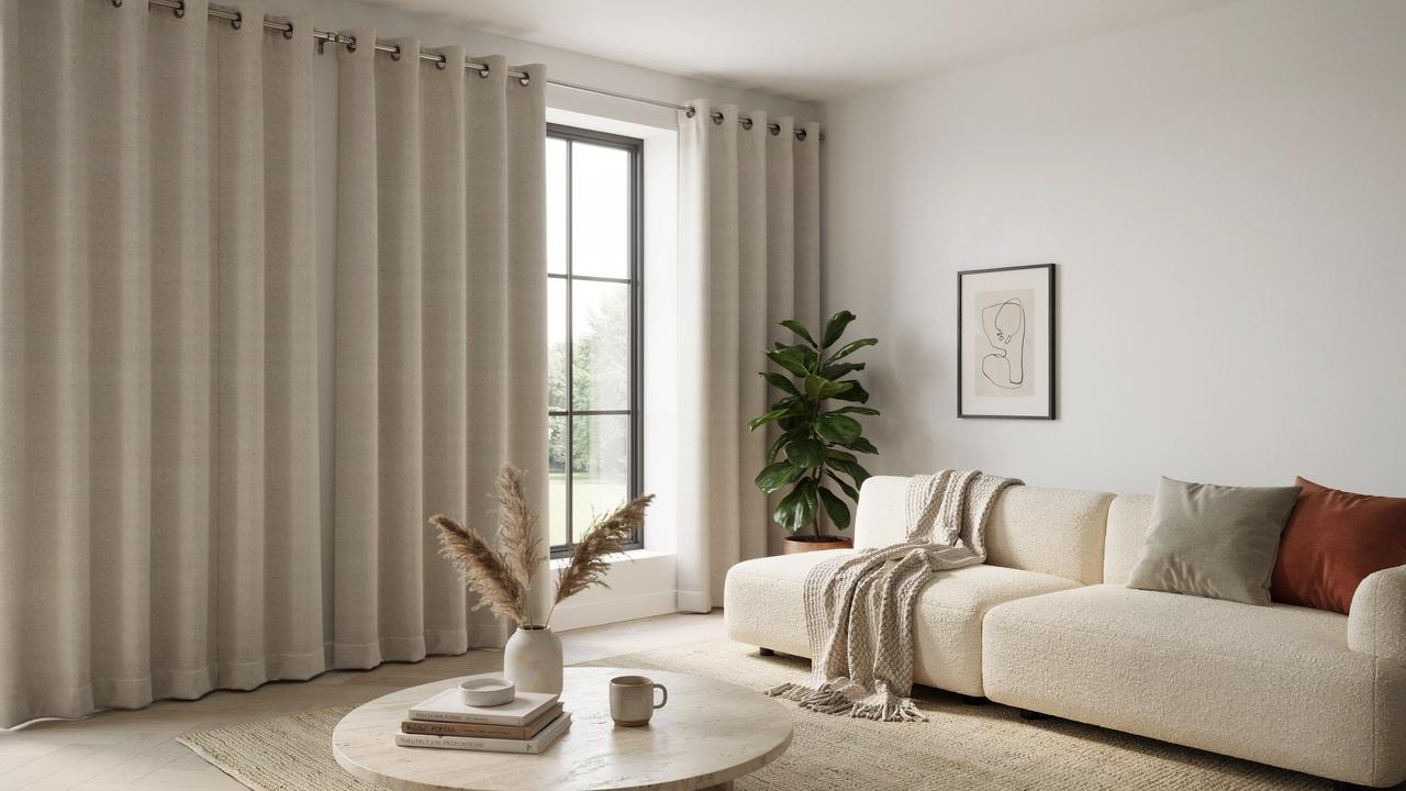 Modern living room featuring elegant grommet curtains with visible metal eyelets hanging beside a sunlit window.