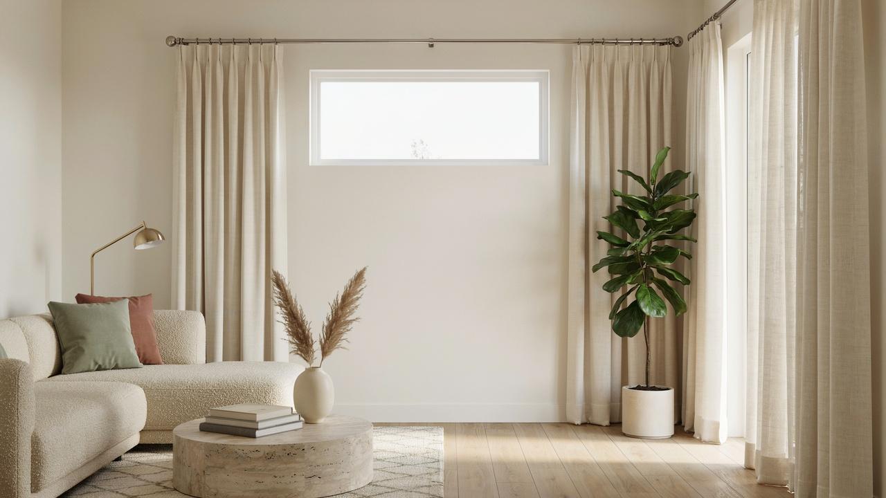 A small window with curtains hung wider than the frame to create the illusion of a larger and wider window.