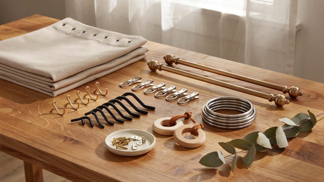 Various curtain hooks and rings displayed beside a curtain panel and rod in a decorative flat-lay arrangement.