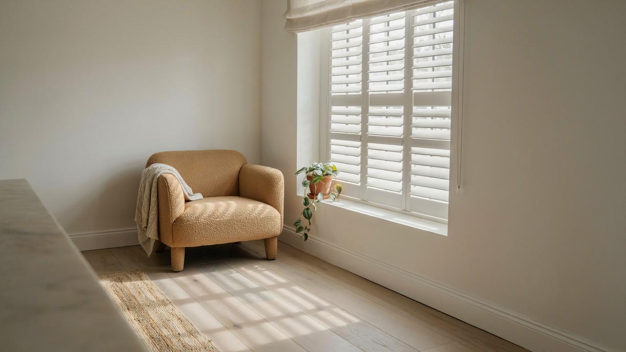Modern window with white inside mount plantation shutters installed neatly within the window frame in a bright living room.