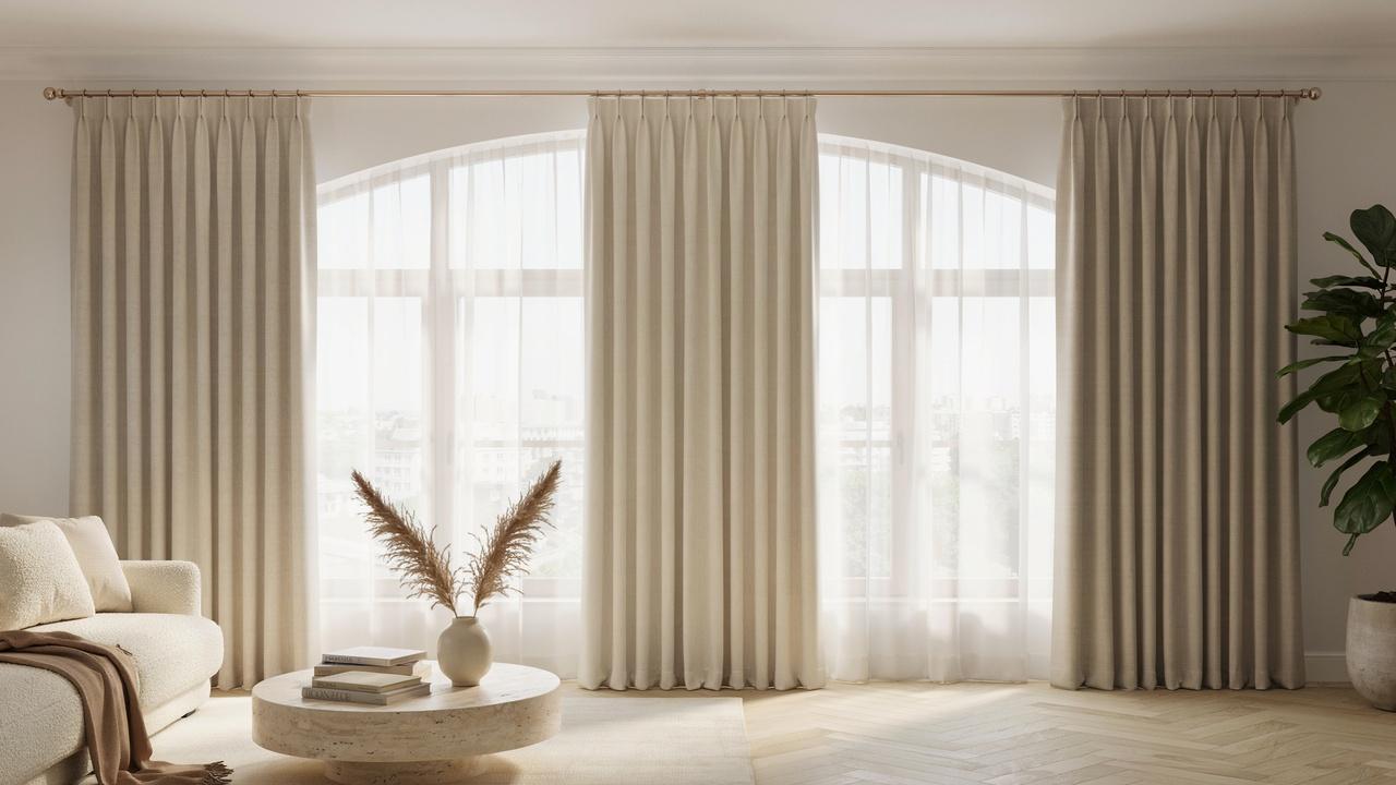 Classy pencil pleat curtains with neatly gathered folds hanging in a bright modern living room.