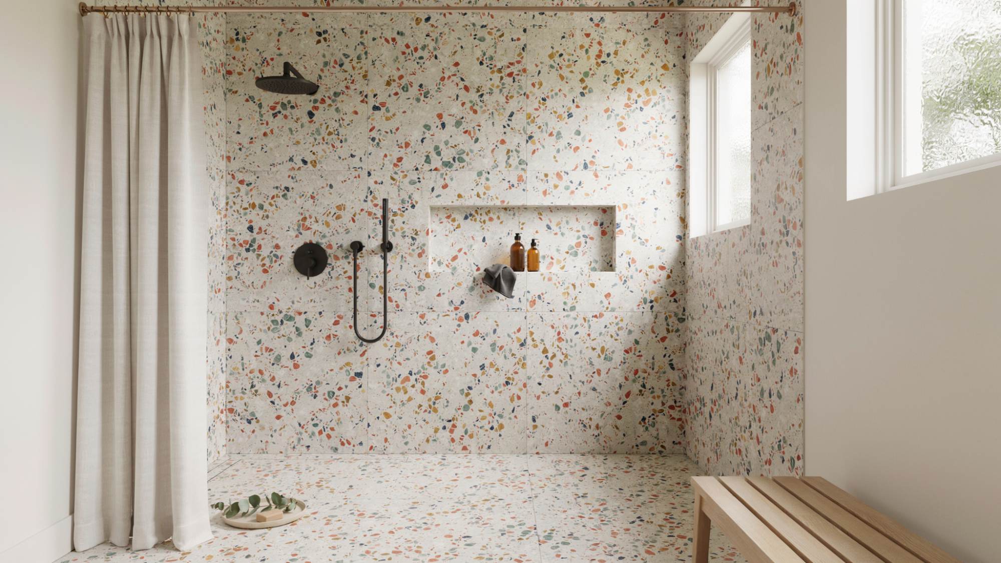 Walk-in shower with terrazzo tile surfaces and a simple neutral curtain.