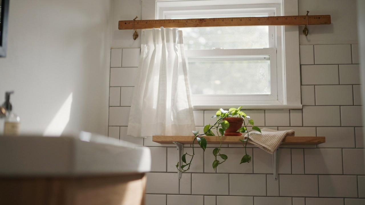 Wooden yardstick used as a curtain rod for a small window.