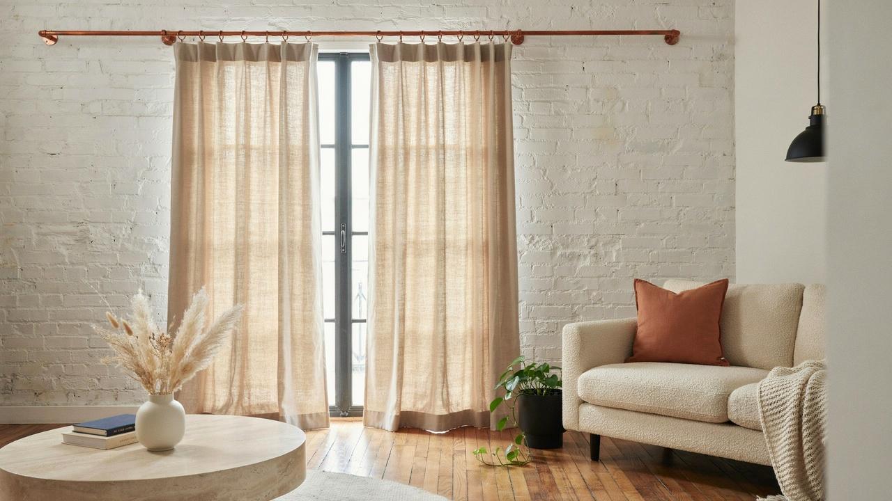 Copper pipe curtain rod with copper fittings above a bright window.