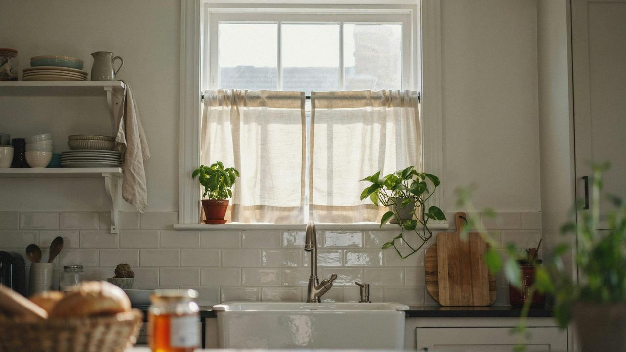 Cafe curtain rod holding a short curtain over the lower half of a kitchen window.