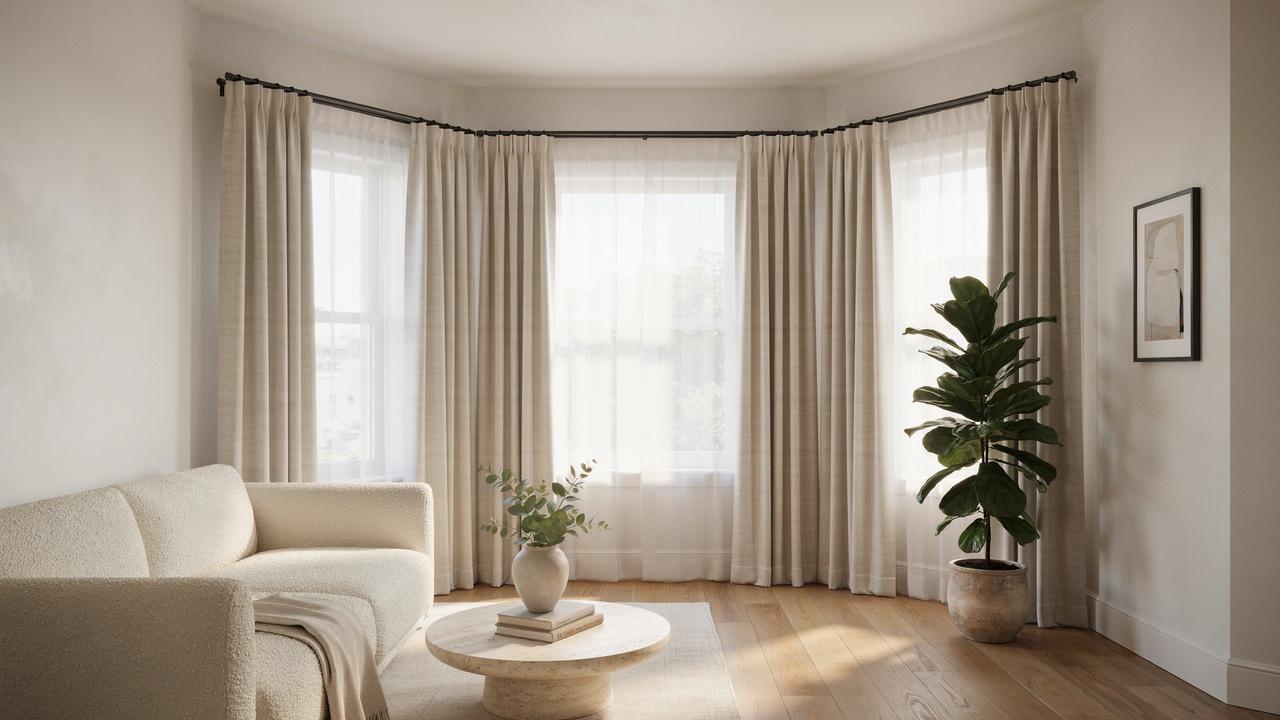 Bay window with beige curtains and sheer panels, boucle sofa, round coffee table with plant vase, fiddle leaf tree.