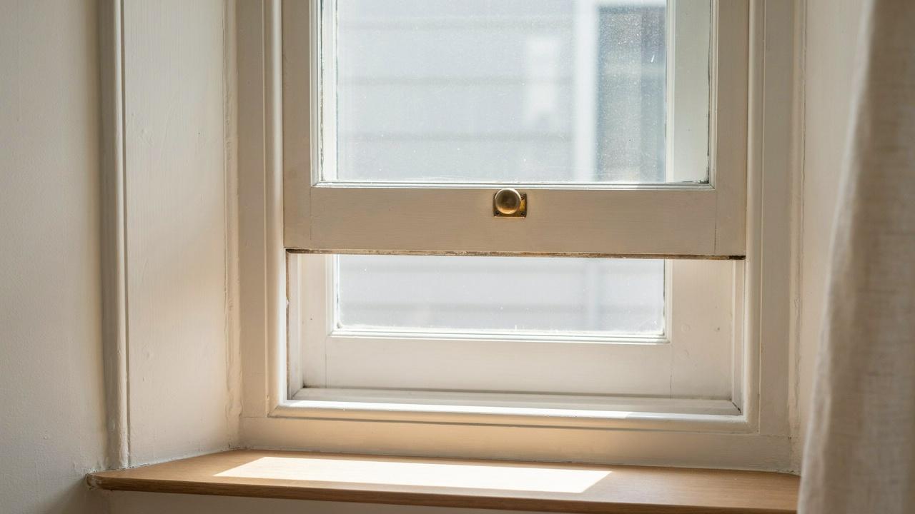 Close-up of a traditional window sash with framed glass, rails, and stiles.