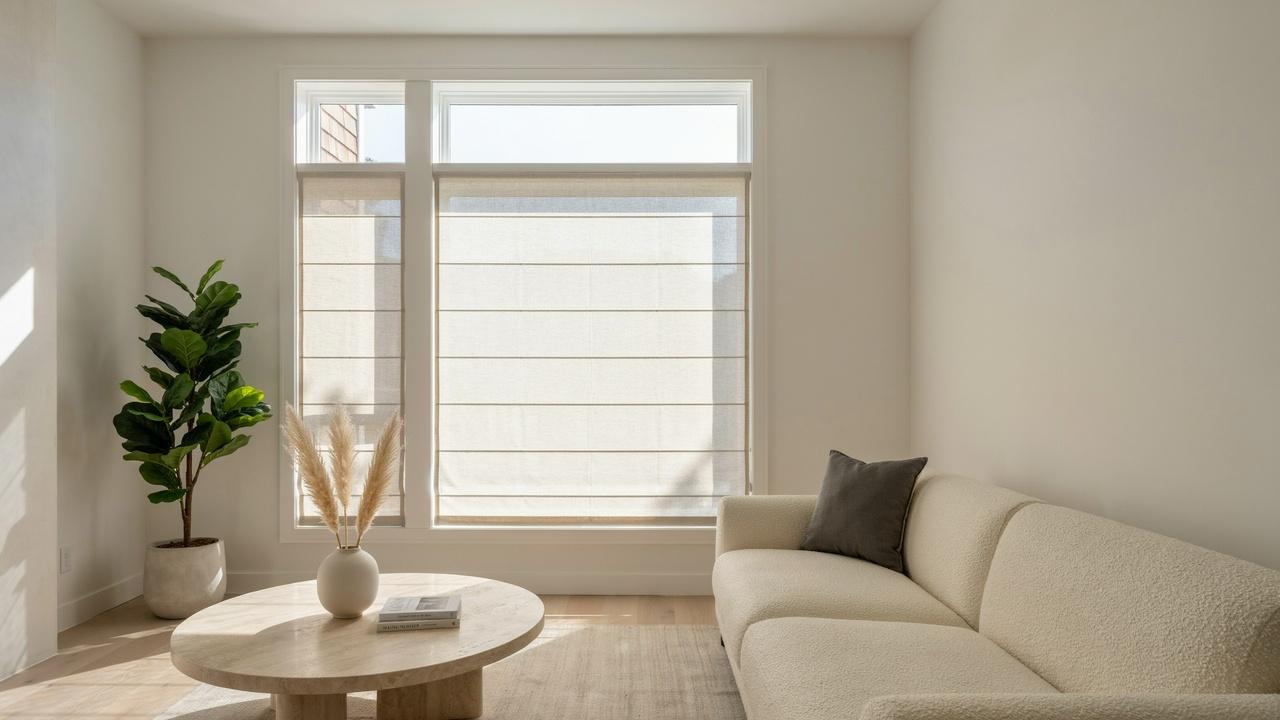 Flat fold Roman shade with broad horizontal fabric panels covering a modern living room window.