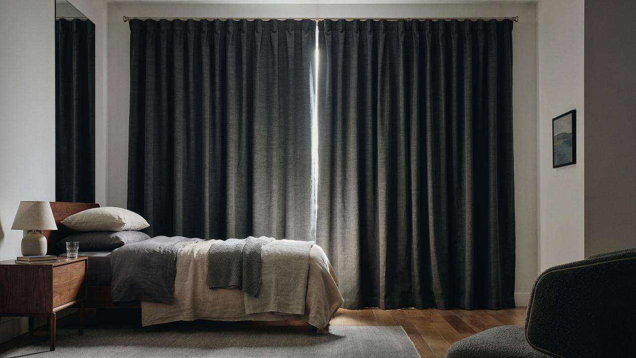 Thick blackout curtains covering a bedroom window to block light.